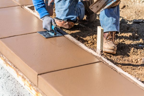 Construction Worker Using Stainless Steel Edger On Wet Cement Forming Coping Around New Pool.